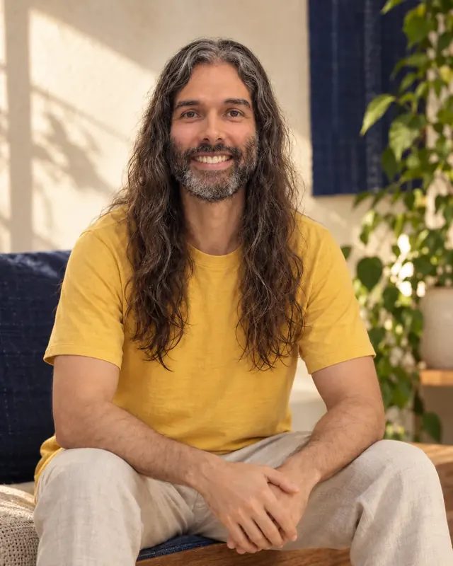 Filipe Morgado sentado, sorrindo, de camiseta amarela, numa sala clara com luz natural.